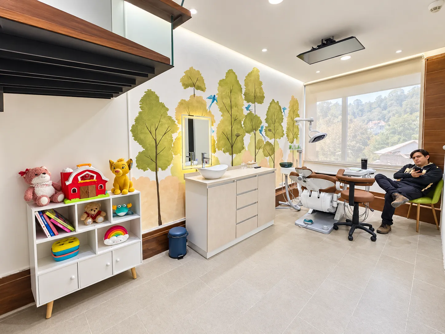 Consultorio de Gratia con mural de árboles y rincón para niños con juguetes y libros